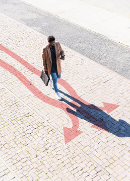 Well-dressed man walking along arrows stretching across sidewalk