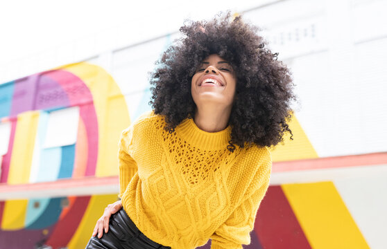 Cheerful woman with eyes closed smiling while standing outdoors