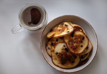 pancakes with berries in a plate. Coffee in a transparent cup. Breakfast

