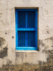 Fototapeta na wymiar closed blue window with shutters in the window opening of an old building or house, a fragment of the facade, texture
