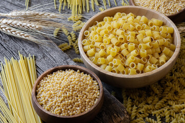 Various raw pasta on wooden background, uncooked food concept