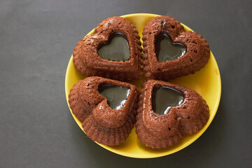 Heart shaped chocolate muffins on a yellow saucer on a gray background. Baking for Valentine's Day.