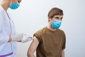 Male getting Covid-19 vaccine. Close up doctor making injection to patient in medical mask. Syringe...