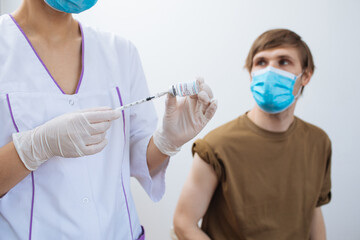 Male getting Covid-19 vaccine. Close up doctor making injection to patient in medical mask. Syringe of coronavirus vaccine. Man receives jab vaccinated. Pacents gets a flu shot. Inject in arm