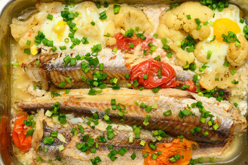 hake fish baked with vegetables close view, baking tray with tomatoes, broccoli and spices, home cooking