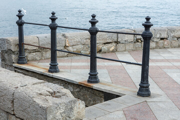 Cast-iron railing on the embankment against the background of the sea.