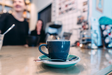 Cup of black coffee, spoon, wooden table, at a cafe