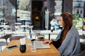 Portrait of female student using net-book while sitting in cafe