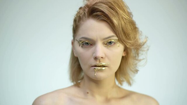 Gold face art. Girl with golden makeup. Fashion art skin. Woman gold portrait closeup.
