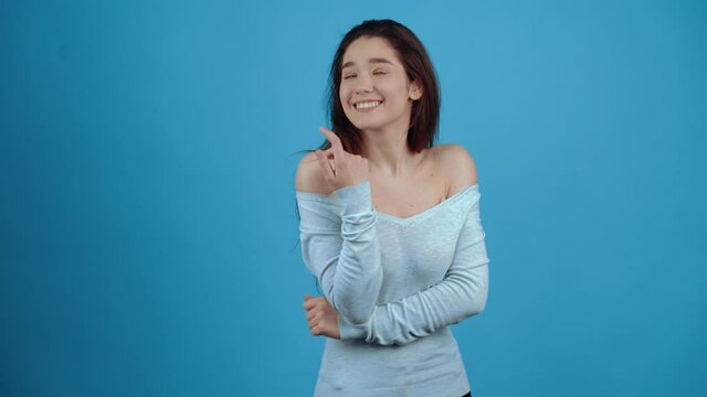 Hey you, yes you, come here Beautiful girl inviting to approach, making beckoning gesture and smiling with alluring playful expression. indoor studio shot isolated on blue background