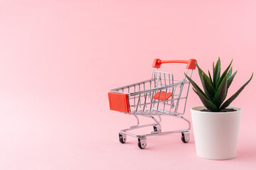 Shopping trolley on light pink background with a copy space.