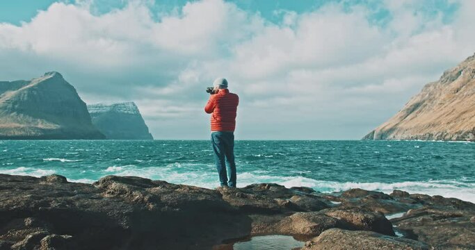 Man taking pictures of the mountains and the ocean. 