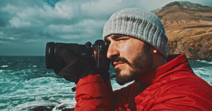 Closeup of a man taking photos in front of the ocean.
