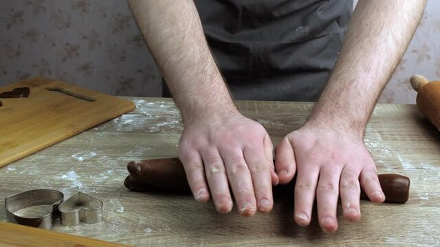 A young cook is kneading the gingerbread dough, on a wooden table on which there is flour. Baking concept