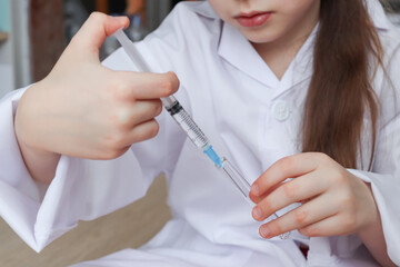 nurse with syringe.
A child in the uniform of a nurse holds a syringe with a flask in his hands, close-up side view.