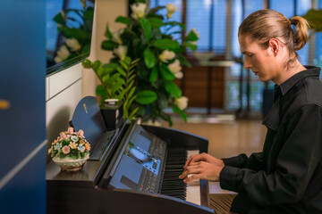 caucasian musician playing belectric piano in hotle lobby