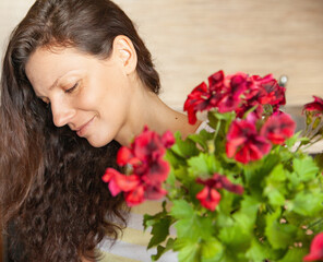 Fototapeta premium Adult brunette with blooming plant at home