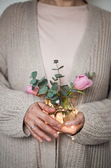 Faceted vase with flowers in female hands with illumination and rings.