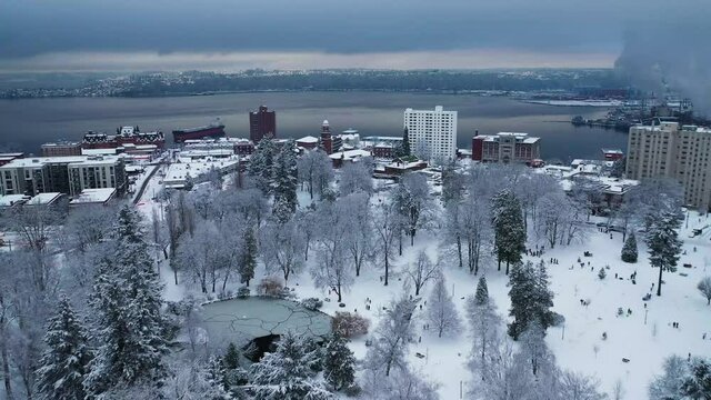 Aerial flyover snowy Wright Park with many people having fun in snow During Winter In Tacoma, Washington.
