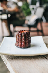 Caneles de bordeaux, French sweet dessert serve with tea or coffee wooden table background. Selective focus. Food issue.