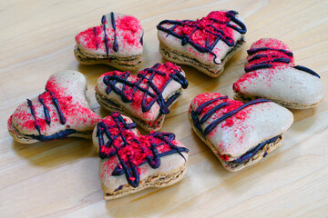 Heart shaped macaron cookies filled with chocolate ganache with raspberry dust