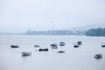 Fototapeta premium Zemun Quay (Zemunski Kej) in Belgrade, Serbia, on the Danube river, seen in autumn, during a foggy afternoon. Boats can be seen in front, and Belgrade center in background