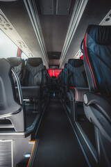 A vertical wide-angle view of an empty interior of a regular intercity bus with rows of leather...