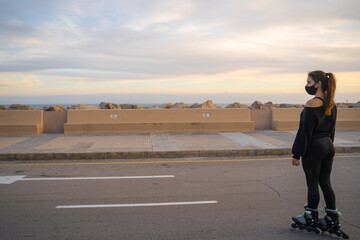 Caucasian girl with mask skating on roller skates on the promenade of Palma de Mallorca at a beautiful sunset, Spain (Perfect for copyspace)