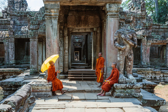 Three monks with umbrella sitting in a temple, Angkor