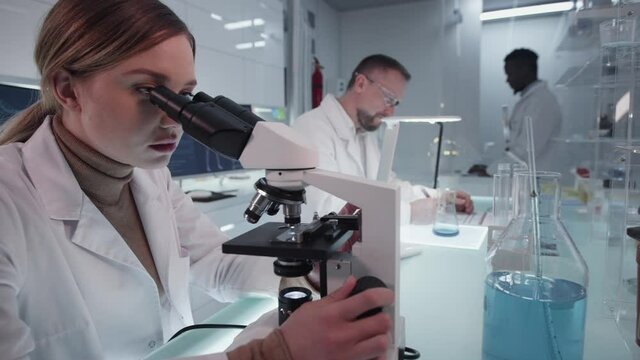 Diverse scientists studying medical samples. Using computers and microscopes. Modern laboratory interior
