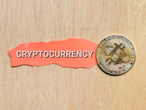 Selective focus phrase Cryptocurrency written on red paper strip with golden bitcoin. Cryptocurrency concept.
