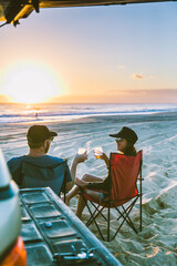 couple drinking cocktail watching sunset on beach