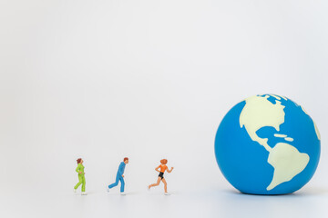 Global sport health concept. Group of runner miniature figure people running to mini world ball on white background with copy space.