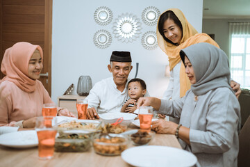 breaking the fast. muslim asian with hijab having iftar dinner together at home sitting on dining table