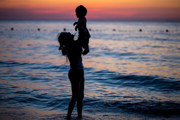 Mother and son playing on the beach at the dawn time.