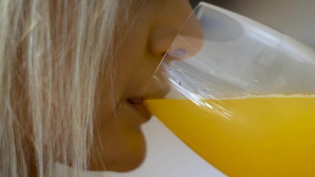 Close up shot of a blonde women drinking orange juice