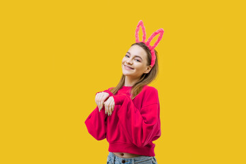 young woman, blonde, wearing pink bunny ears and a red sweater on a yellow background