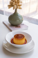 Soft focus Pudding Dessert caramel pudding in a white plate is placed on a white table