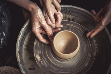 Hands of the master potter and vase of clay on the potter's wheel