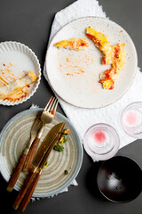 Pile of empty and dirty plates with food leftovers on dark background.