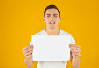 Guy with white sheet of paper mockup yellow background Copy Space