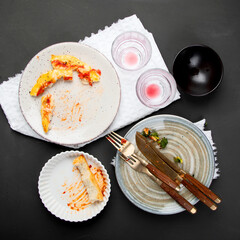 Pile of empty and dirty plates with food leftovers on dark background.