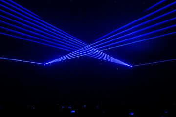 Beautiful blue laser beam in concert with crowded people holding the smartphone.