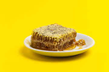 Honey in combs in a plate on a yellow background