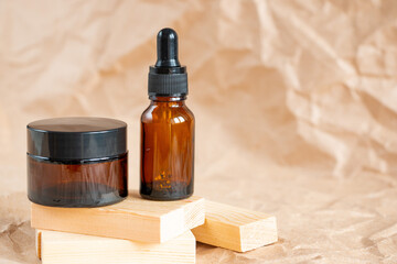 Cometic bottles made of amber glass on crumpled craft paper. Skin care products packaging design. Spa concept.