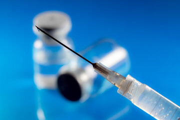 selective focus of syringe and vial for vaccine on a blue background, in Brazil