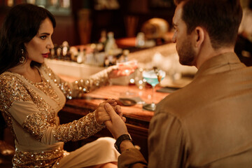 Young handsome man in bar accompanied by elegant lady, dating, flrt and drink cocktails