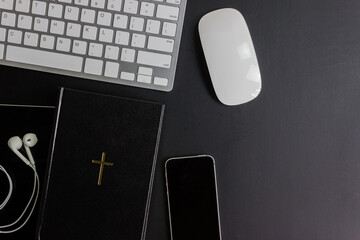 Top view of holy bible with new testament, gadgets dark background