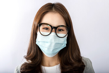 Close-up front view of A beautiful young Asian girl is wearing a face mask to protect the pollution or covid19 virus disease. White background in the studio. Healthcare and virus pandemic concept
