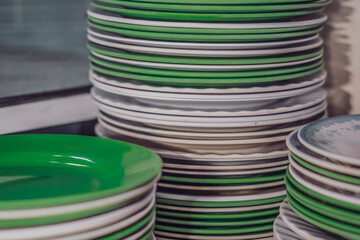 Close-up shot high stack storage of melamine plastic round white green clean flat plates after...
